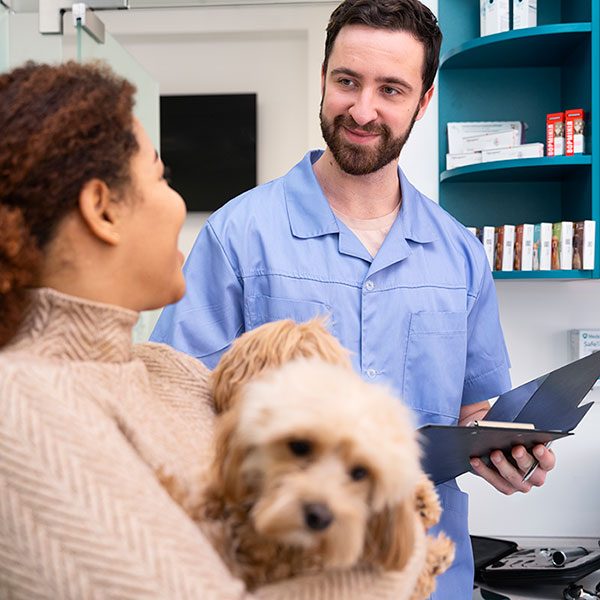 Veterinário atendendo cão e sua tutora em ambiente hospitalar